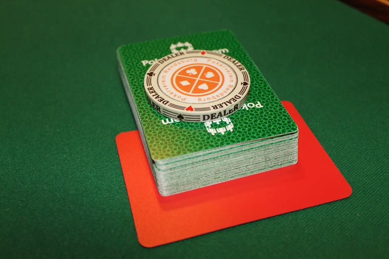 Kortlek och dealerknapp på ett grönt pokerbord